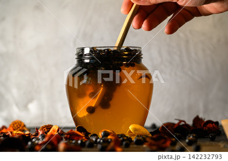 Chokeberries and honey in a glass jar Chokeberries and honey in a glass jar 142232793