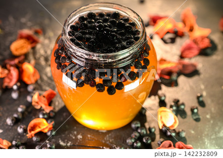 Chokeberries and honey in a glass jar Chokeberries and honey in a glass jar 142232809