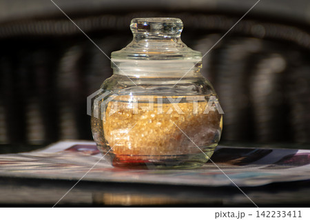 Brown sugar crystals stored clear glass jar lid representing sweetener kitchen ingredient food storage baking everyday pantry essentials 142233411