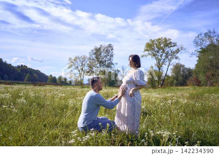 mature couple expecting baby posing together in wild flower meadow in summer mature couple expecting baby posing together in wild flower meadow in summer 142234390