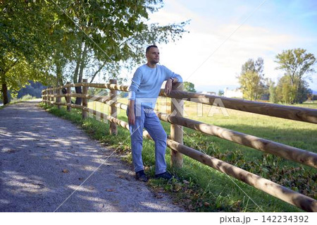 handsome mature man smiling while standing on sunny countryside path handsome mature man smiling while standing on sunny countryside path 142234392