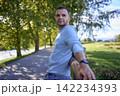 handsome mature man smiling while standing on sunny countryside path 142234393