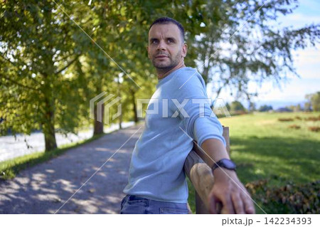 handsome mature man smiling while standing on sunny countryside path 142234393