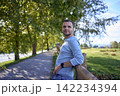 handsome mature man smiling while standing on sunny countryside path 142234394