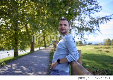 handsome mature man smiling while standing on sunny countryside path handsome mature man smiling while standing on sunny countryside path 142234394