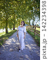 pregnant mature woman in floral dress walking on sunny rural pathway 142234398