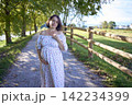 pregnant mature woman in floral dress walking on sunny rural pathway 142234399