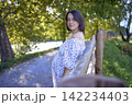 pregnant mature woman in floral dress walking on sunny rural pathway 142234403