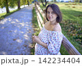 pregnant mature woman in floral dress walking on sunny rural pathway 142234404