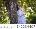 pregnant mature woman in floral dress walking on sunny rural pathway 142234407