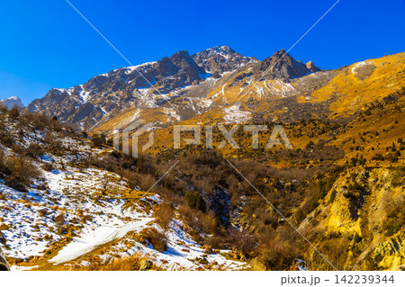 Snowy Mountain Landscape with Golden Slopes and Clear Blue Sky Snowy Mountain Landscape with Golden Slopes and Clear Blue Sky 142239344