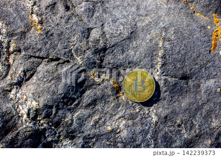 Gold Cryptocurrency Coin on Rough Rock Surface Gold Cryptocurrency Coin on Rough Rock Surface 142239373