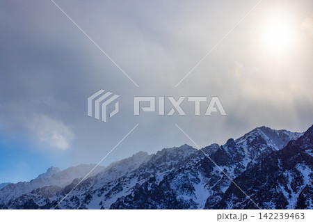Snow-covered mountain range under dramatic cloudy sky 142239463