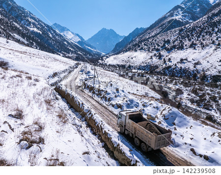 Dump Truck Hauling Gravel on Snowy Mountain Road Dump Truck Hauling Gravel on Snowy Mountain Road 142239508