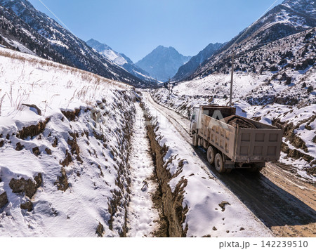 Dump Truck Hauling Soil on Snowy Mountain Road Dump Truck Hauling Soil on Snowy Mountain Road 142239510