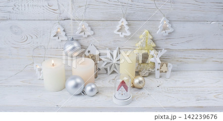 Christmas decorations with candles and ornaments on a white wooden surface. Christmas atmosphere in home interior. Christmas decorations with candles and ornaments on a white wooden surface. Christmas atmosphere in home interior. 142239676