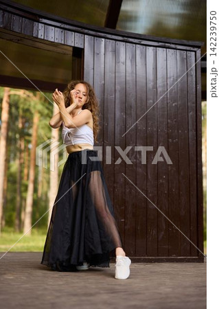 Female model showcasing elegant dance fashion in natural setting Female model showcasing elegant dance fashion in natural setting 142239750