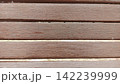 Straight on close up framing horizontal brown painted wooden slats of an outdoor park bench perfect for wooden backgrounds 142239999