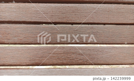 Straight on close up framing horizontal brown painted wooden slats of an outdoor park bench perfect for wooden backgrounds 142239999