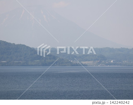 霞の向こうにそびえる山と静かな湖面 夏の逆光の風景 霞の向こうにそびえる山と静かな湖面 夏の逆光の風景 142240242