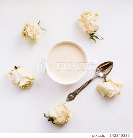 Still life of a cup of coffee or cappuccino with dry white roses around. Square. Still life of a cup of coffee or cappuccino with dry white roses around. Square. 142240386