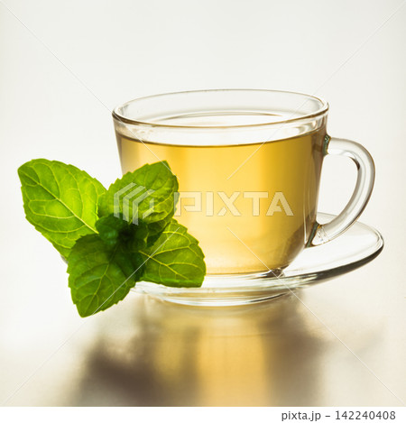Glass cup of green tea and mint leaves on white. 142240408