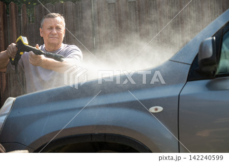 Senior man washing dirty car with pressure washer outdoors Senior man washing dirty car with pressure washer outdoors 142240599