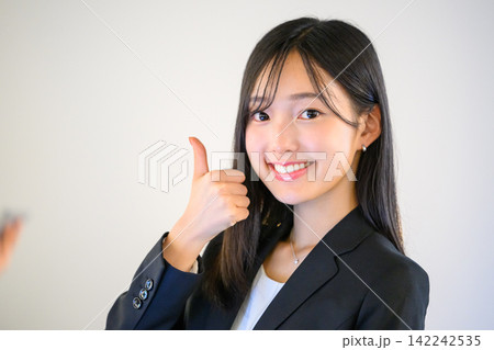オフィスでサムズアップをして笑顔を見せる女性社員 オフィスでサムズアップをして笑顔を見せる女性社員 142242535