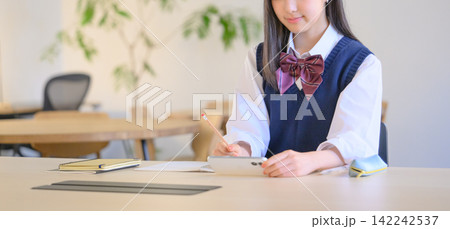 勉強中の女子高生がスマートフォンで調べ物をする様子 142242537