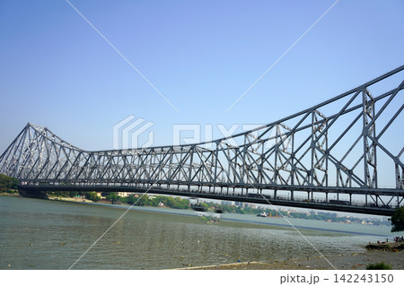 Howrah Bridge standing majestic over the Hooghly River under a clear blue sky in Kolkata Howrah Bridge standing majestic over the Hooghly River under a clear blue sky in Kolkata 142243150