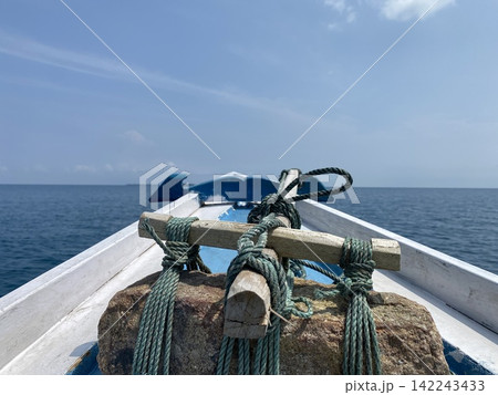 View from the bow of traditional wooden boat sailing across the open tropical sea View from the bow of traditional wooden boat sailing across the open tropical sea 142243433