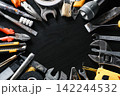 Assorted hand tools arranged around open center on black background 142244532