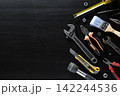 Assorted hand tools arranged on dark wooden surface with large empty copy space 142244536