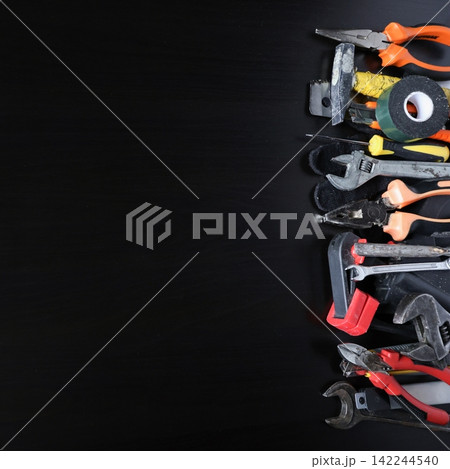 Assorted hand tools arranged along right edge on dark wooden surface, copy space for repair Assorted hand tools arranged along right edge on dark wooden surface, copy space for repair 142244540