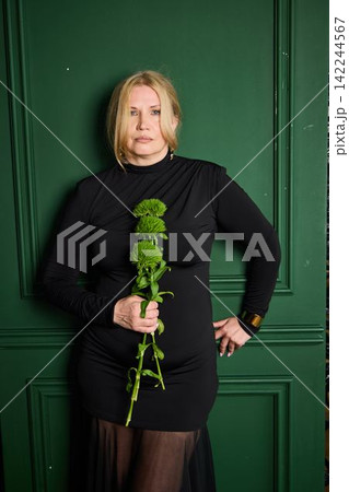 Determined white woman hand on hip holding green flowers Determined white woman hand on hip holding green flowers 142244567