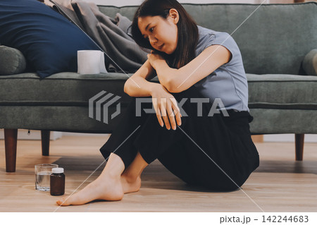 Young Asian woman sitting in bed and holding her head in pain with headache, feeling depressed and suffering 142244683