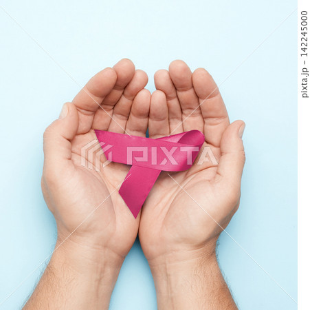 Male hands holding a pink ribbon, symbol of breast cancer awareness Male hands holding a pink ribbon, symbol of breast cancer awareness 142245000