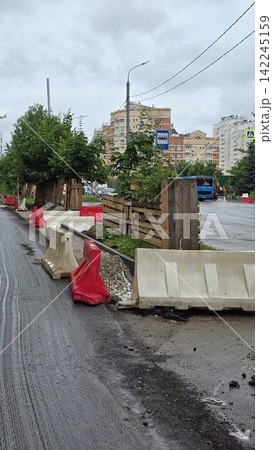 Road construction site with plastic barriers and temporary wooden fences in a city residential district zone. Road construction site with plastic barriers and temporary wooden fences in a city residential district zone. 142245159