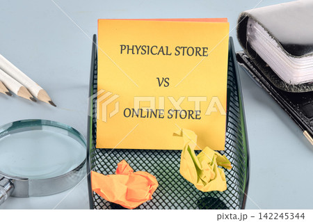 Retail business concept with Physical Store vs Online Store text on a yellow sticky note in a black metal mesh holder 142245344