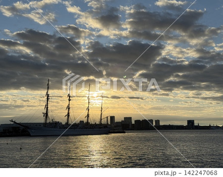 金色の朝日に浮かぶ帆船のシルエットと青空 金色の朝日に浮かぶ帆船のシルエットと青空 142247068