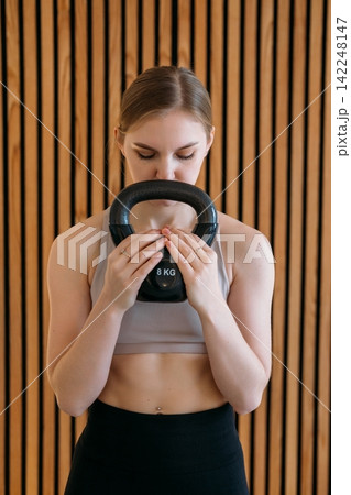 Kettlebell workout. Athlete training activity. Young woman holding heavy weight in modern fitness studio. Strong muscle power skill. Kettlebell workout. Athlete training activity. Young woman holding heavy weight in modern fitness studio. Strong muscle power skill. 142248147