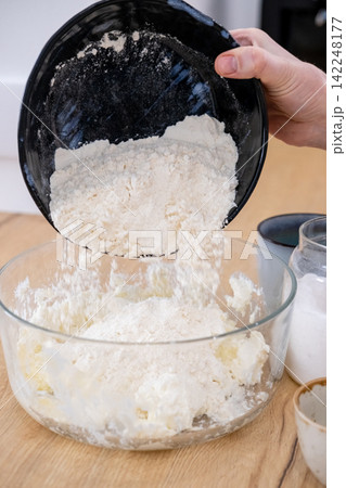 Preparing dough. Adding flour. Woman chef hand pouring culinary ingredient in glass bowl cooking tasty homemade pastry meal at kitchen table. Preparing dough. Adding flour. Woman chef hand pouring culinary ingredient in glass bowl cooking tasty homemade pastry meal at kitchen table. 142248177