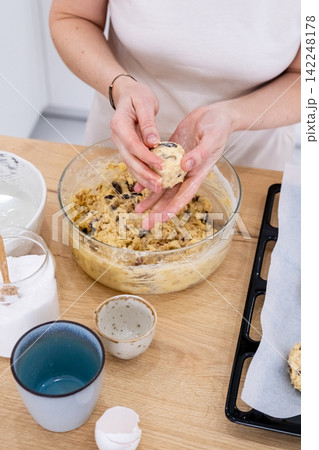Home food. Cookies making. Woman chef hand shaping peanut dough ball pieces on table with measuring cookware preparing for baking on tray. 142248178