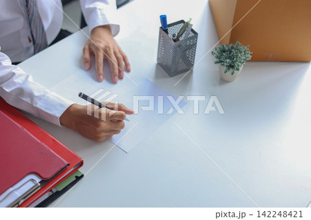 Employee signing exit paperwork next to box of personal belongings. Employee signing exit paperwork next to box of personal belongings. 142248421