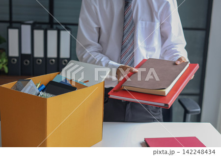 Business professional packing up belongings after getting laid off. 142248434
