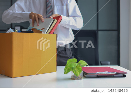 Business professional packing up belongings after getting laid off. 142248436