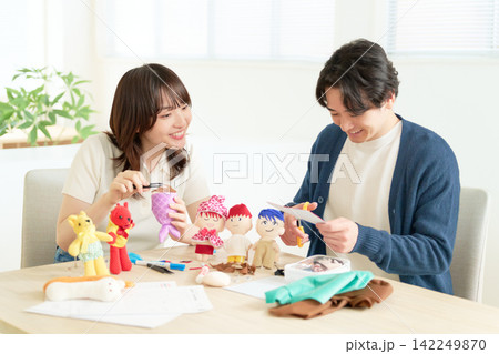 ぬいぐるみの服づくりを楽しむ若いカップル ぬいぐるみの服づくりを楽しむ若いカップル 142249870