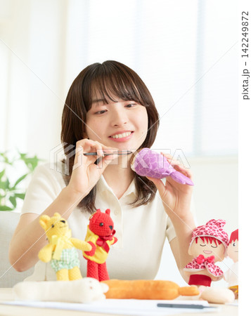 テーブルでぬいぐるみ作りを楽しむ若い女性 テーブルでぬいぐるみ作りを楽しむ若い女性 142249872