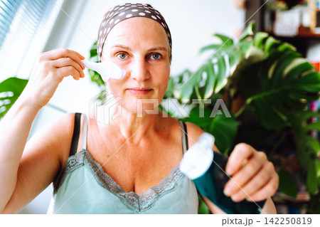 middle-aged woman cosmetic mask on face enjoys free time 142250819