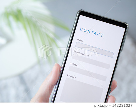 スマートフォンに表示されたお問い合わせフォーム (Contact Us) のWebサイト画面 スマートフォンに表示されたお問い合わせフォーム (Contact Us) のWebサイト画面 142251027